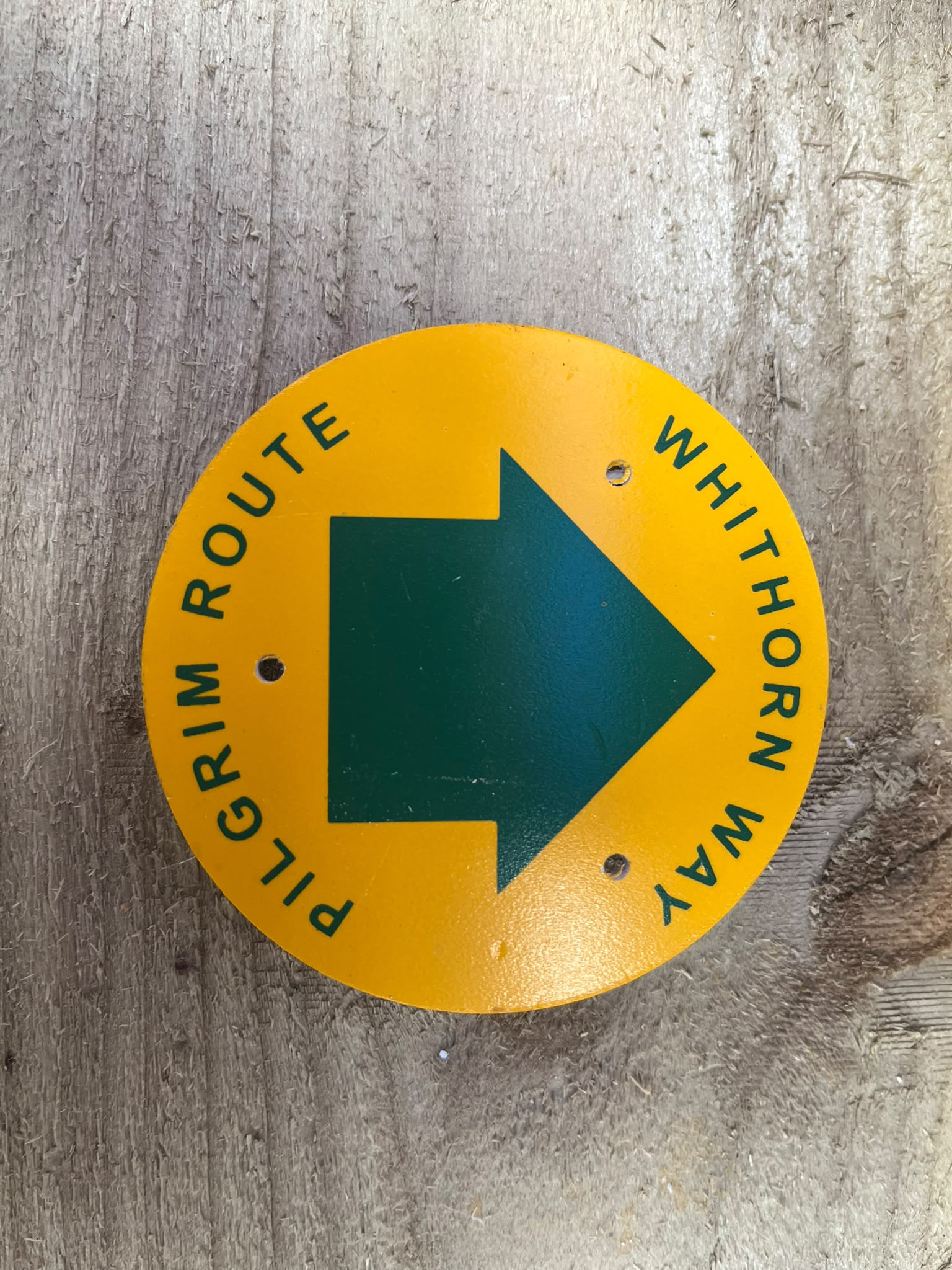 Yellow circular Whithorn Way Pilgrim Route disc with green arrow